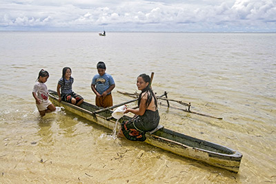 Local children play in shallow water with traditional, hand carved outrigger canoe off Walung, an isolated village in Kosrae Photo by Yvette Cardozo