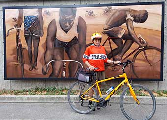 Author standing in front of a mural of black bicycle racers