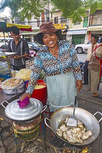 Woman on street cooks pork and shrimp for sale in Phnom Penh, Cambodia.