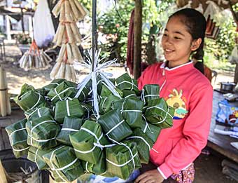 Cambodian girls carrying bundle of sticky rice packets
